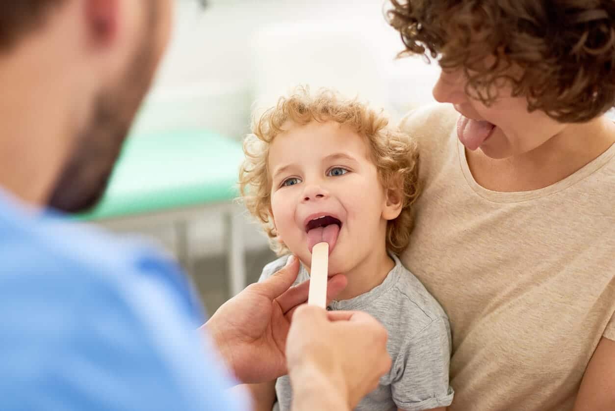 Doctor examining the child's tongue or tonsils